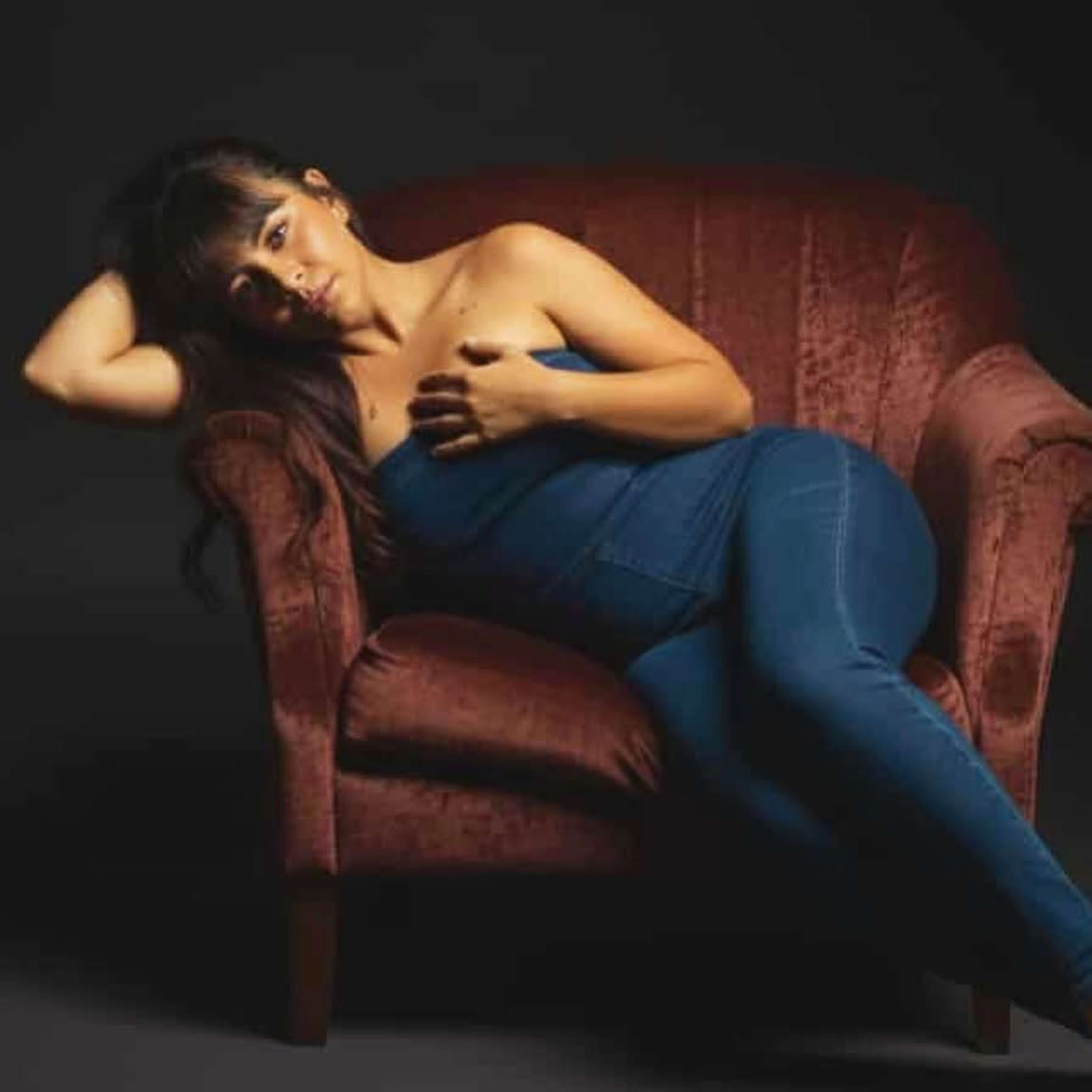 Priya Kaur reclining in a vintage armchair